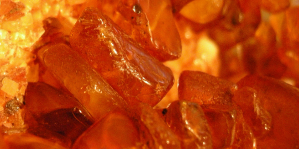 Physical properties of amber. Sun stone properties. An electrified piece of  amber attracts pieces of paper against a gray background. Magnetized resin.  Natural mineral for jewelers. Copal Stock Photo
